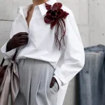 Style vestimentaire 2026 : chemise blanche, pantalon perle, broche rouge
